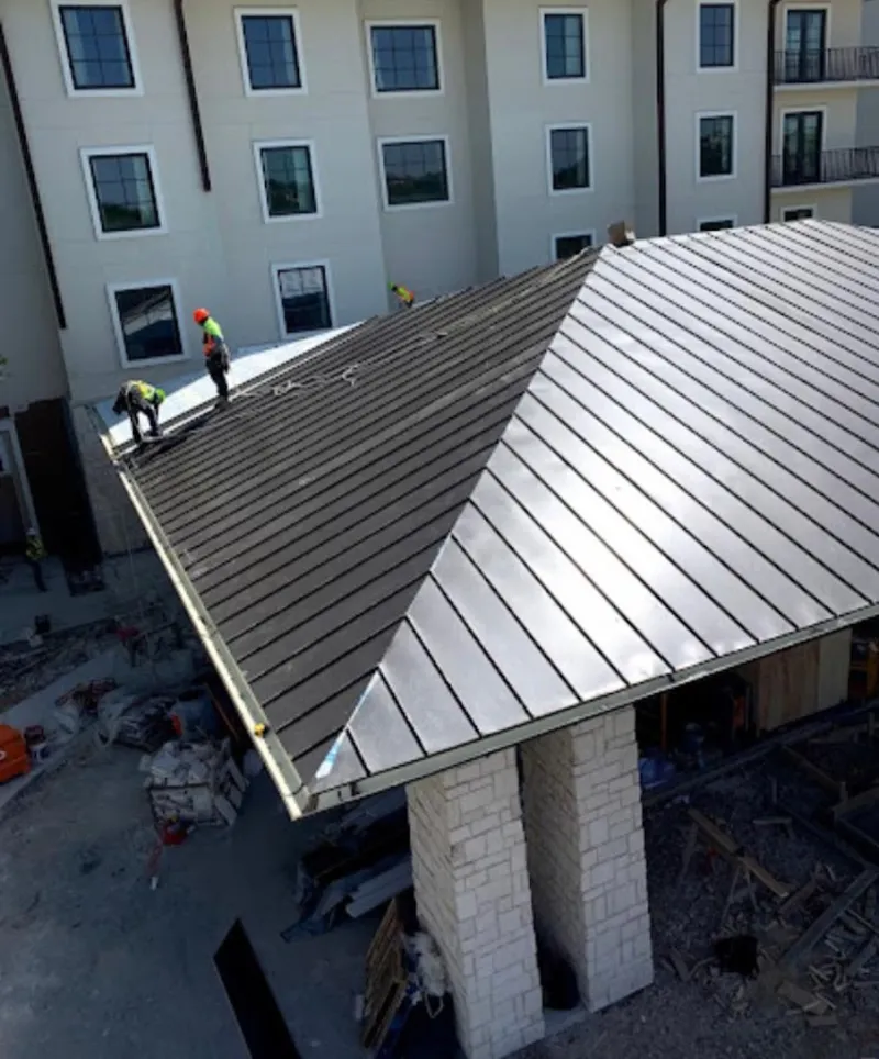 Crew installing standing seam metal roof panels on a commercial project in Swissvale